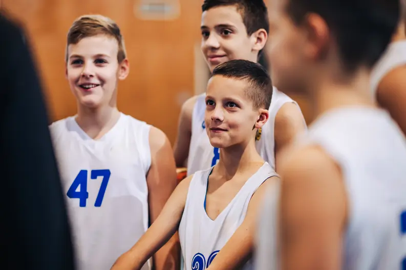 Smiling youth basketball players listening attentively to their coach during a practice session